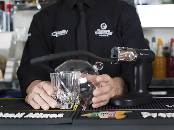 Un barman usa un affumicatore su un cocktail durante il corso di mixology