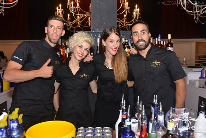 Lo staff bar in divisa nera sorride dietro al bancone di un club
